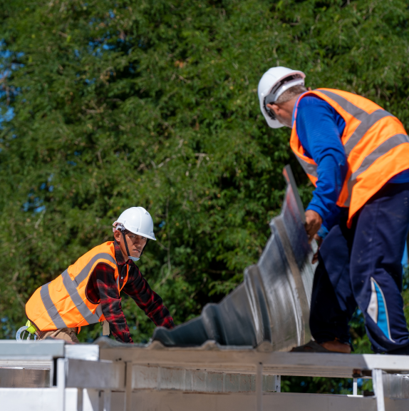 Roofers installing sheet metal panel.